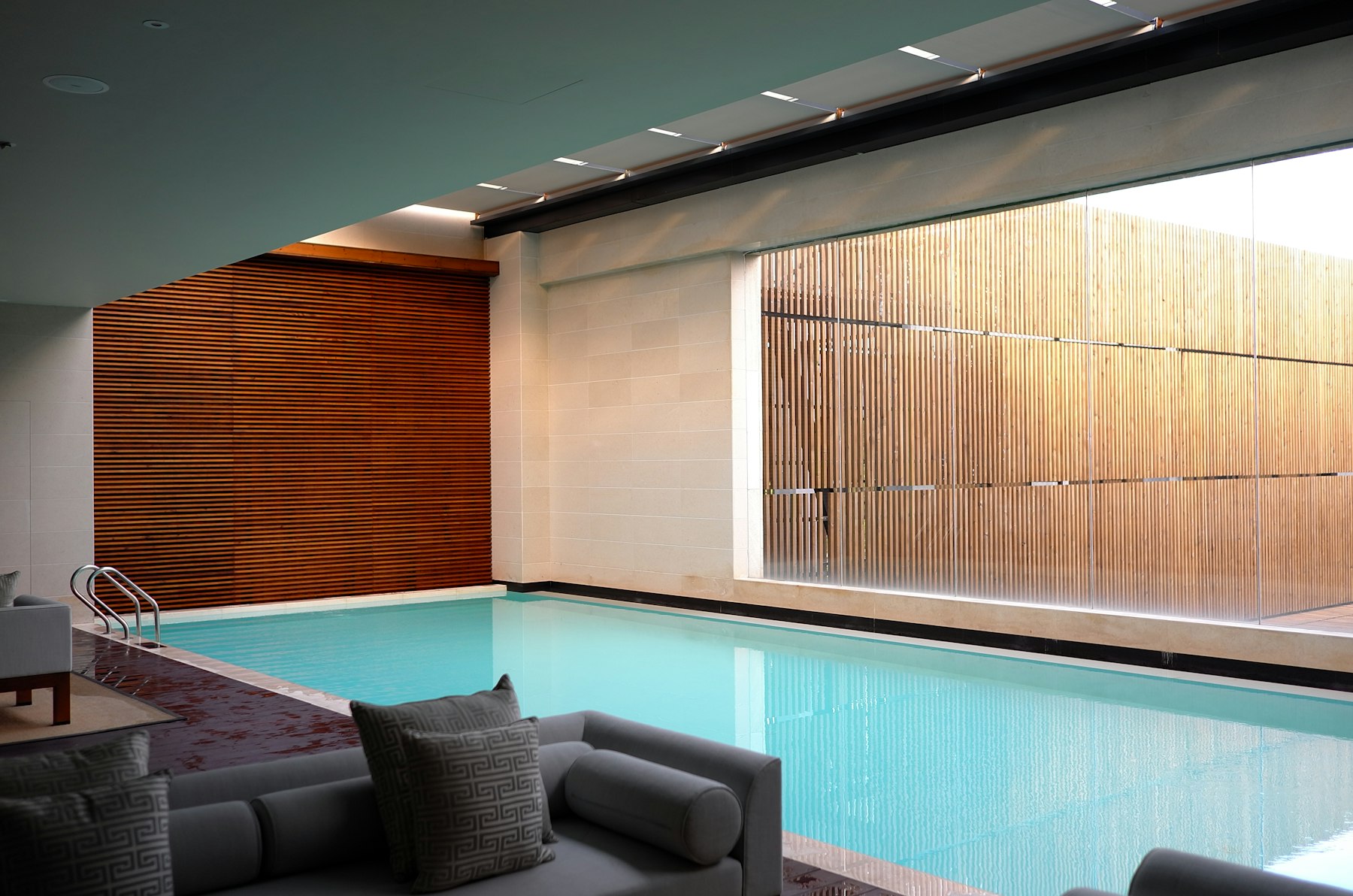 Living room with a full wall of impact glass to the pool