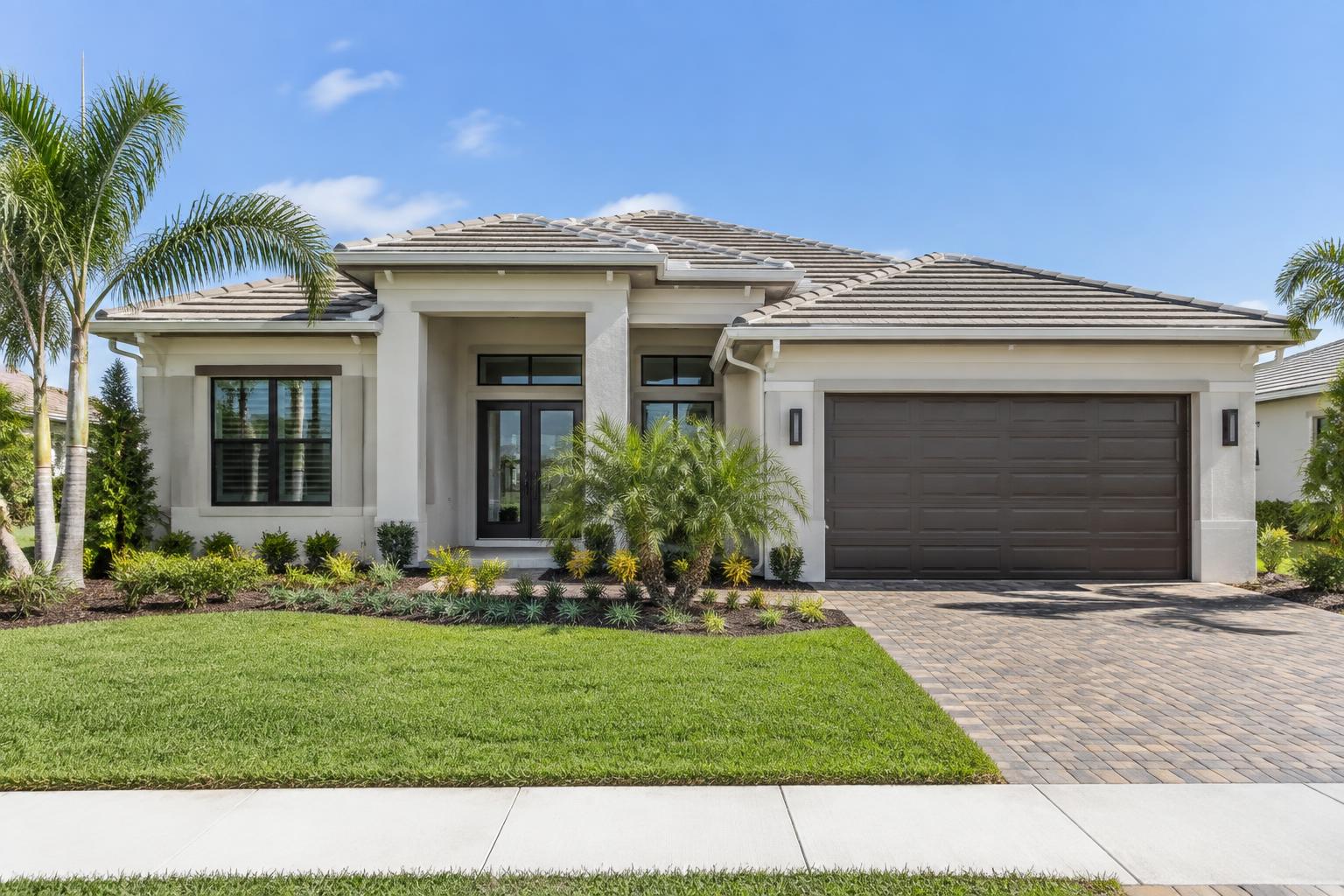 Generic contemporary single-family residential exterior with stucco walls, palm landscaping and a paved drive.
